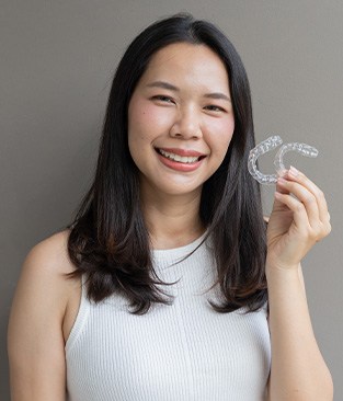 Smiling woman holding two Invisalign aligners