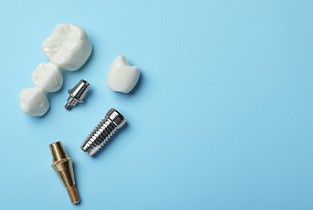 Dental implant and dental bridge parts set against a blue background