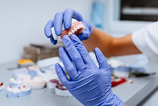 Dental lab technician with gloves working with dentures