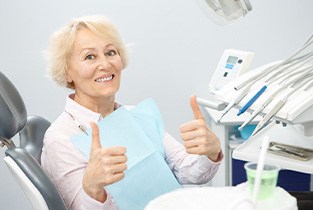 Senior woman in dental chair giving two thumbs up