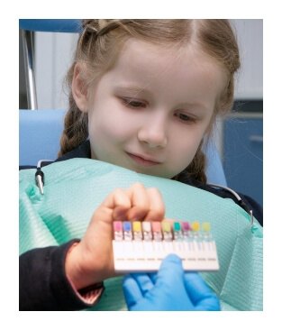 Chid in dental office looking at tooth colored filling color chart