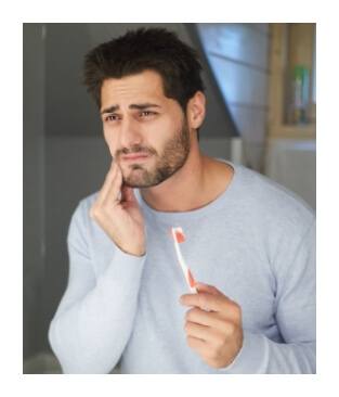 Main in pain while brushing teeth before emergency dentistry visit