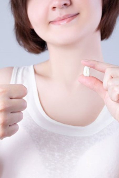Woman holding her extracted tooth and making thumbs up gesture