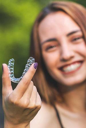 Woman holding an aligner for Invisalign in Rio Rancho, NM