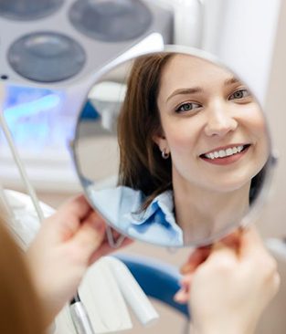 Cosmetic dentistry patient looking at her smile in mirror