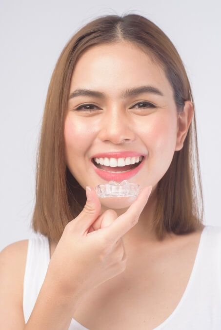 Woman placing clear braces orthodontics tray