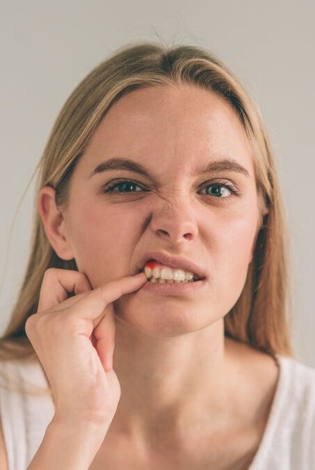 Woman pointing to inflamed soft tissue after gum disease treatment