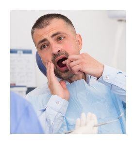 Man in pain pointing to mouth before wisdom tooth extraction