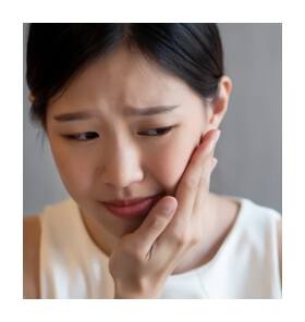 Woman in need of T M J therapy holding jaw in pain