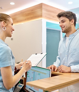 Patient smiling at dental receptionist while discussing price