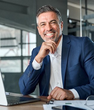 a businessman smiling and sitting at a desk