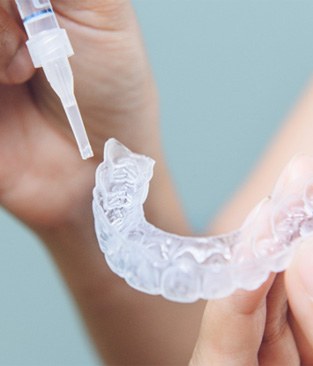 a person putting whitening gel in a tray