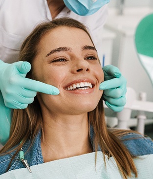 Woman with white teeth smiling at reflection in mirror