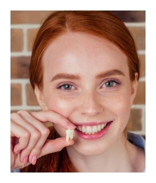 Woman holding up an extracted wisdom tooth next to her smile