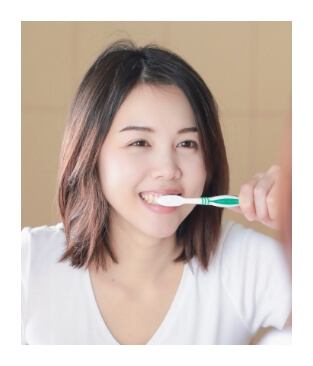Woman brushing teeth to care for smile after wisdom tooth extraction