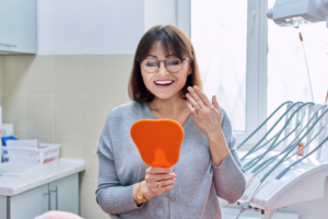 a patient admiring her smile in a handheld mirror