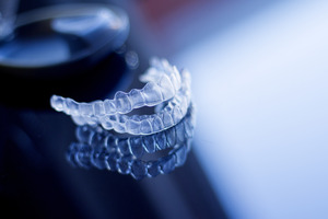 Two Invisalign aligners sitting on reflective surface